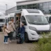 Jong gezin bekijkt camper bij showroom voor kampeervakantie