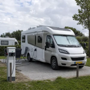 Elektrische Nederlandse camper op een campingplaats bij een laadpaal