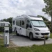 Elektrische Nederlandse camper op een campingplaats bij een laadpaal